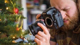 Man 'freelensing' with a camera and a lens, framing a Santa in a plane Christmas decoration