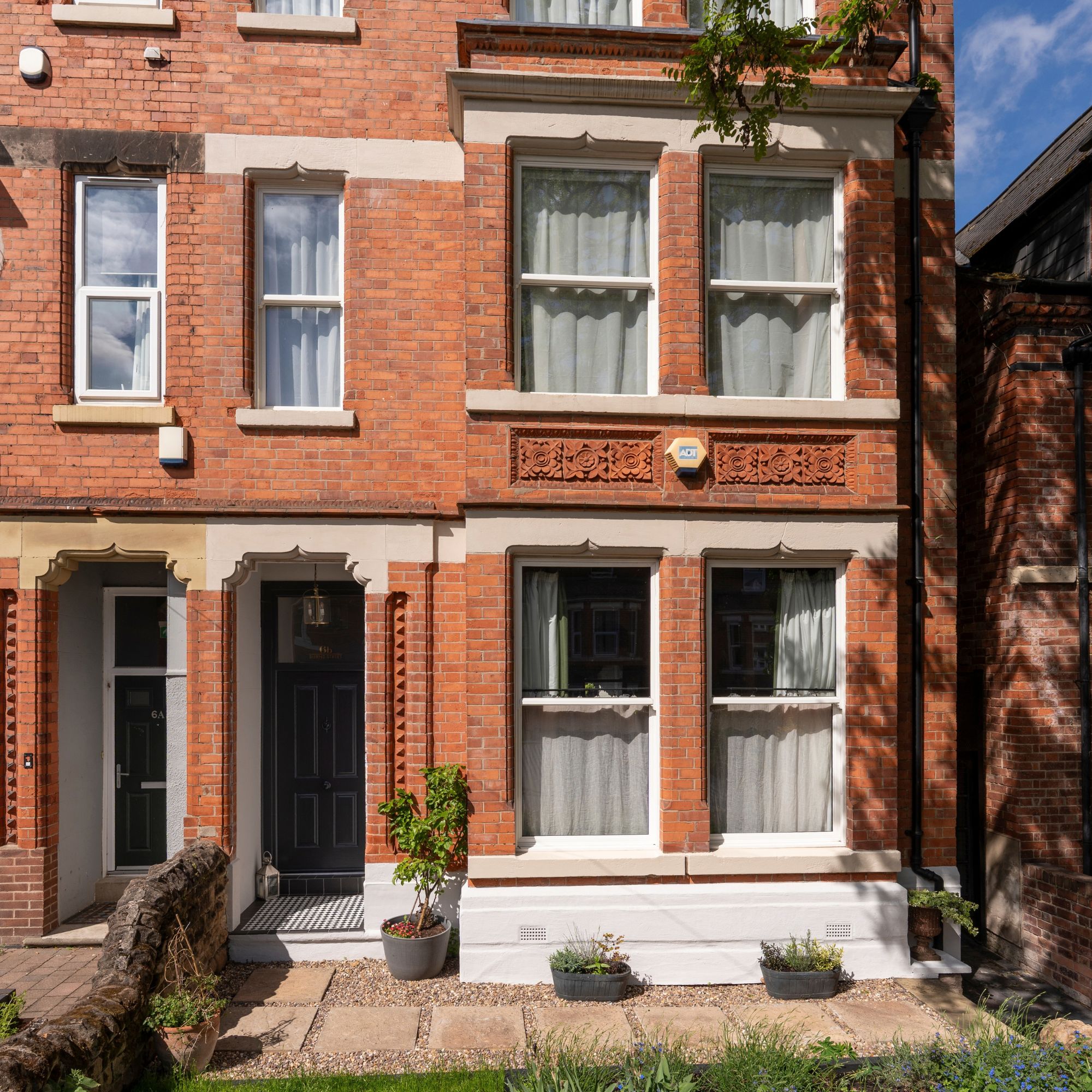 Victorian terraced flats with a blue front door and a paved patio out the front