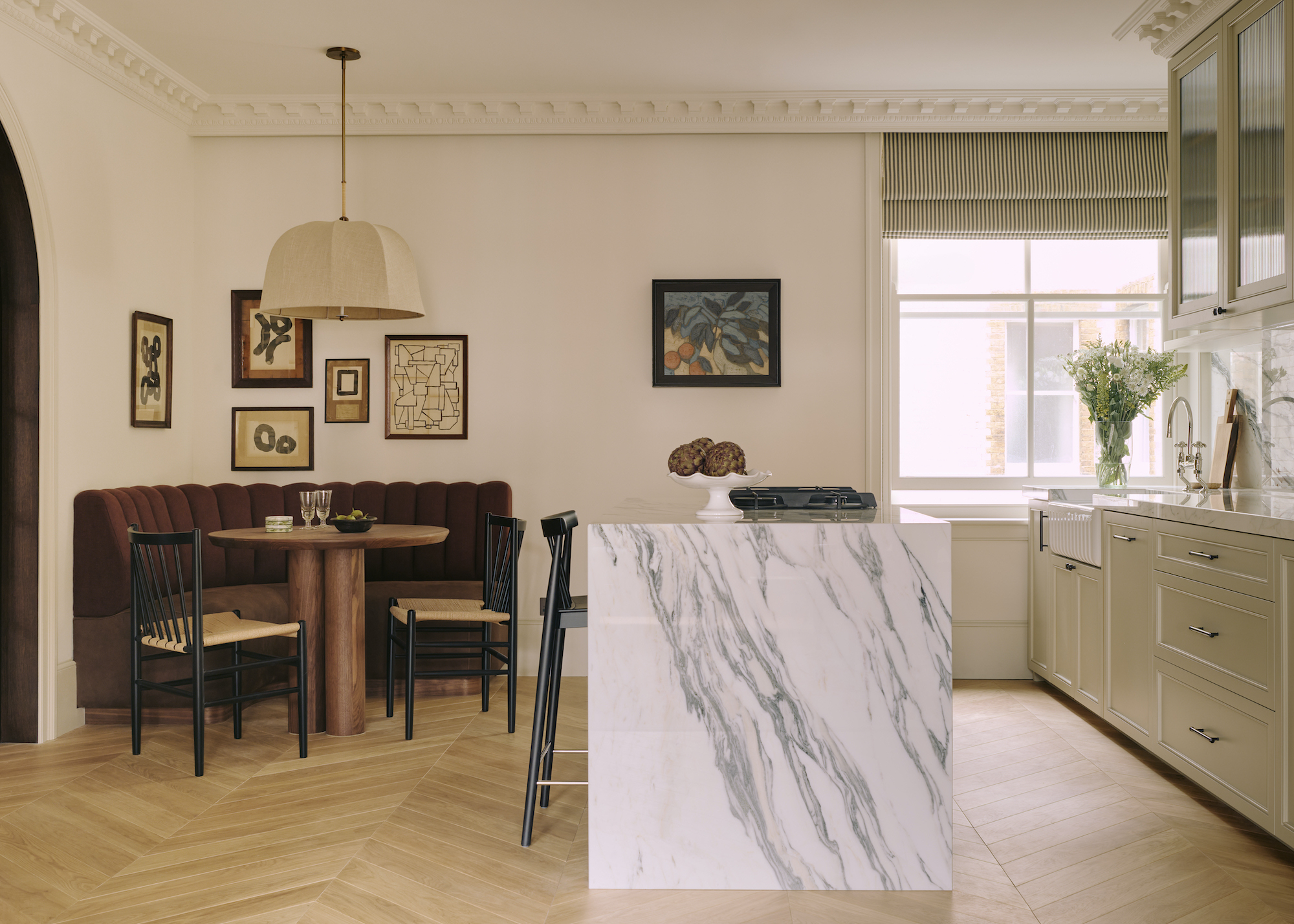 marble island with waterfall edge in a chic kitchen. There is also a dining area in the kitchen.
