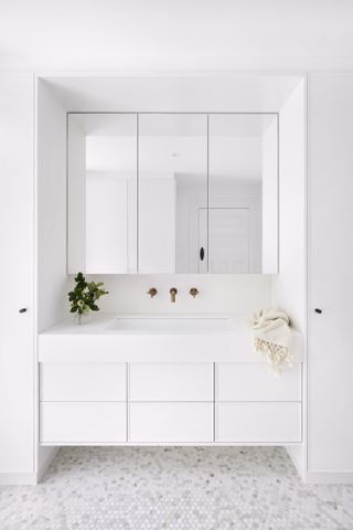 A bathroom with white vanity and walls, and white tiles with grey grout