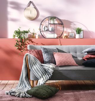 living area with pink wall and wooden floor with grey sofa