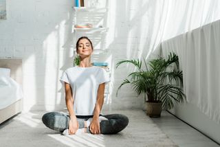 Stay healthy on a budget: beautiful happy girl with closed eyes practicing yoga in lotus position in bedroom in the morning
