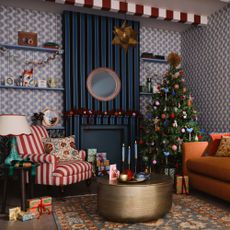 A living room with an orange sofa, a striped chair and a Christmas tree decorated with decorations from the John Lewis Worldly Treasures range