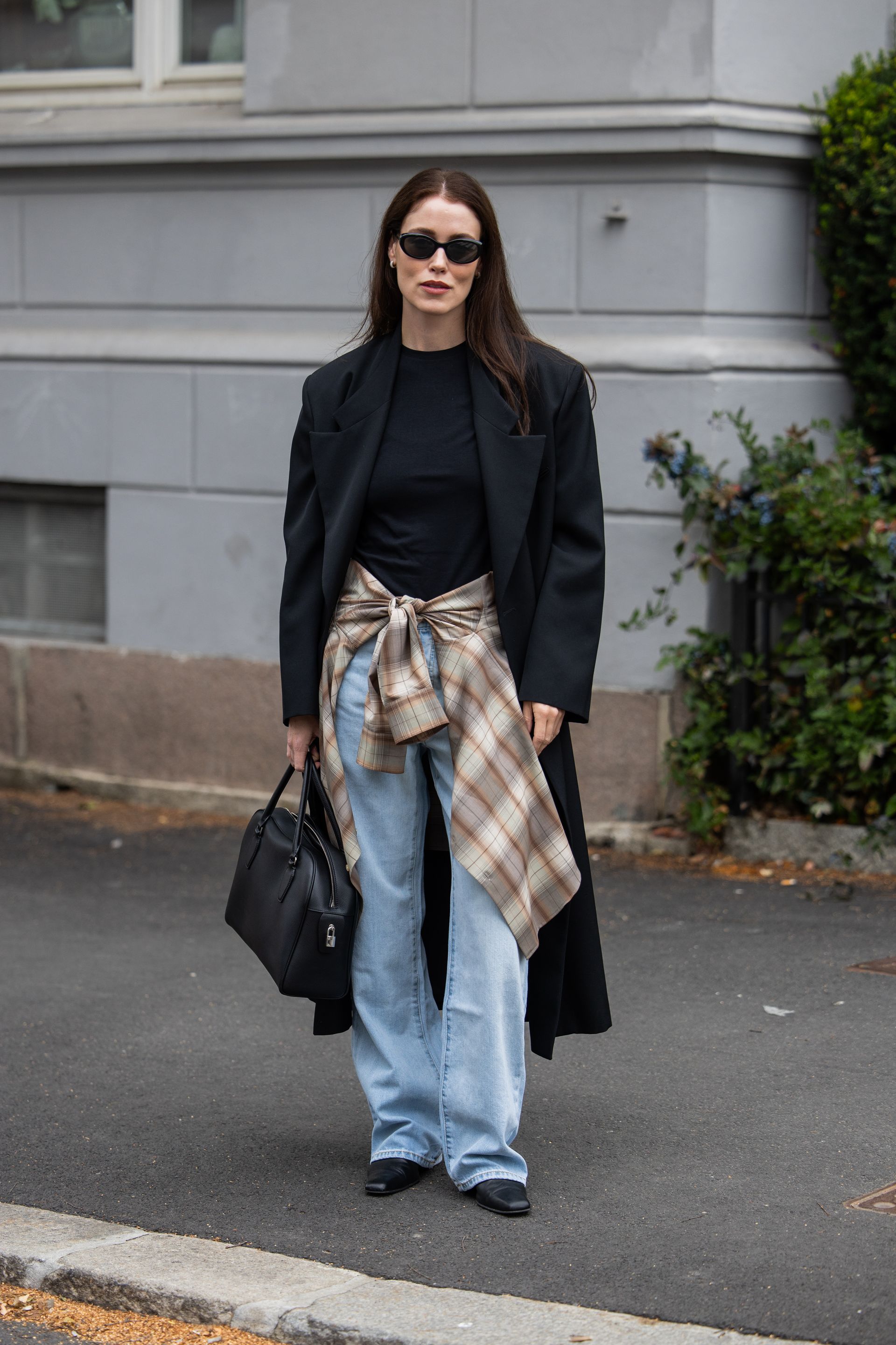A woman wears a plaid shirt tied around her waist.