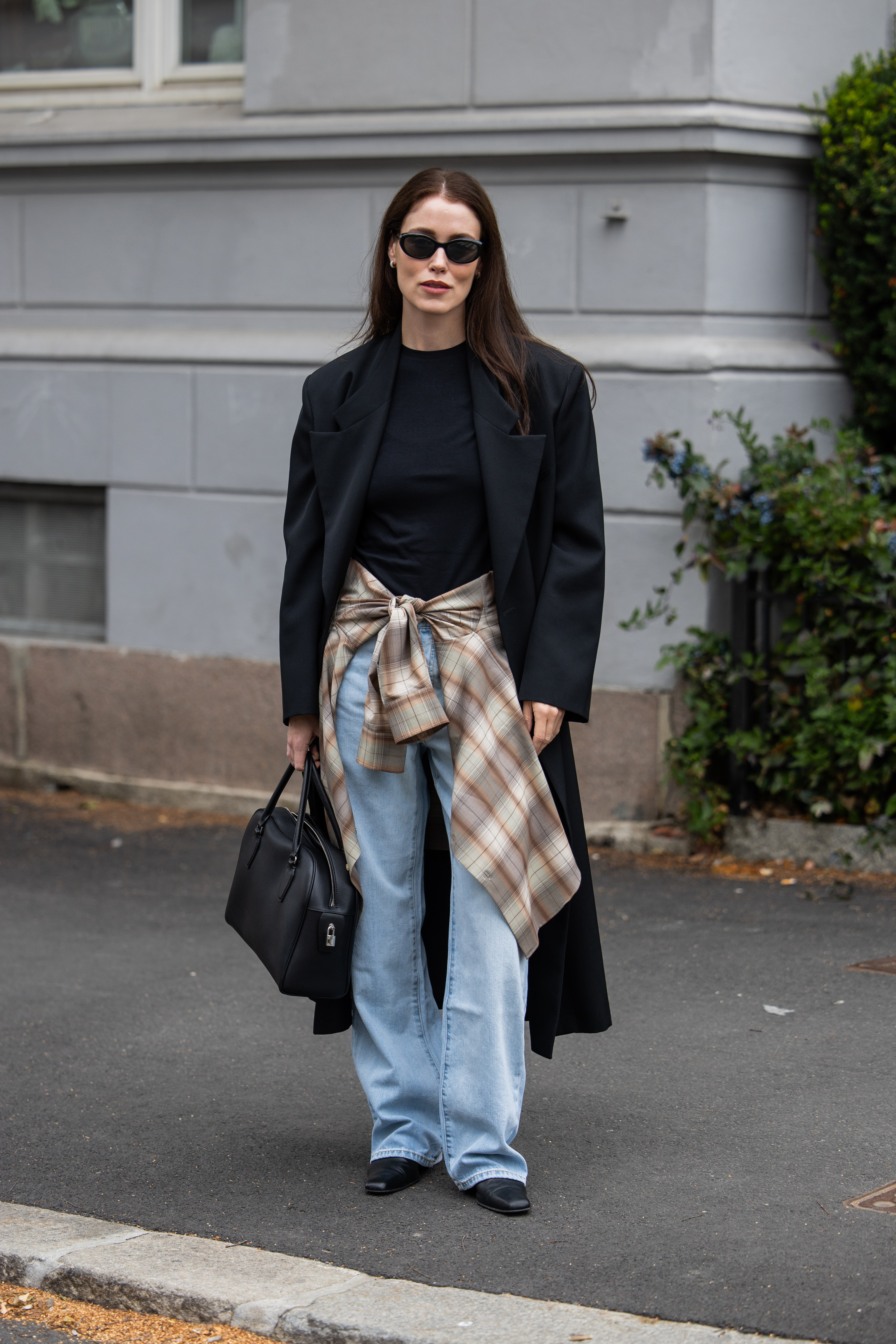 A woman wears a plaid shirt tied around her waist.