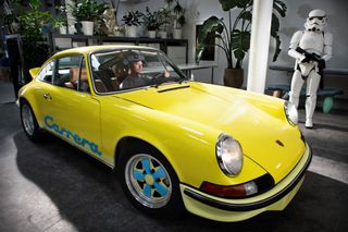 A portrait of Daniel Arsham inside a yellow Porsche
