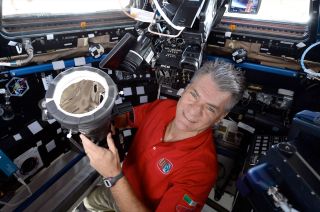 Expedition 52 flight engineer Paolo Nespoli of the European Space Agency (ESA) poses with his camera equipped with a 400mm lens and a solar filter in preparation to photograph the solar eclipse inside the Cupola on the International Space Station.