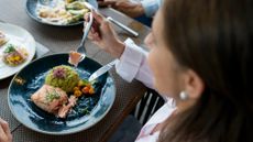 Woman eating salmon at a table