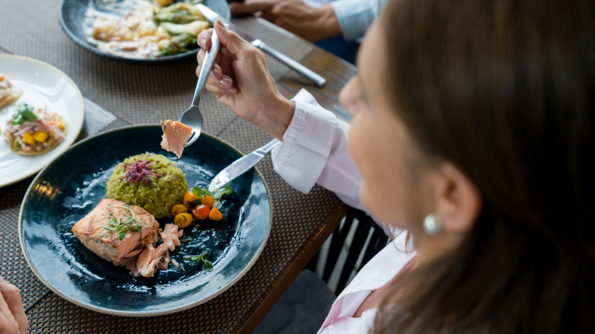 Woman eating salmon at a table