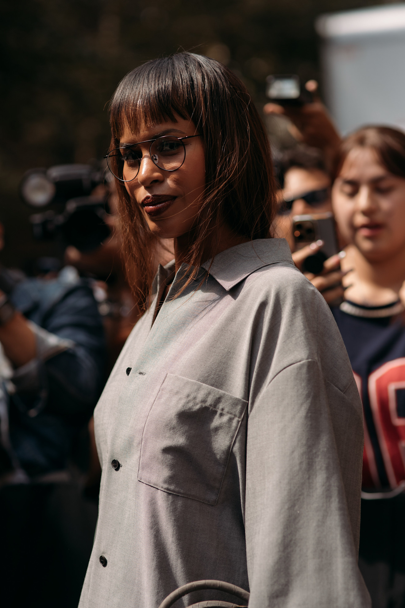 a woman wearing a grey shirt and blunt bangs