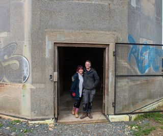 A couple stood in the doorway of the water tower which has a metal fence for a front door