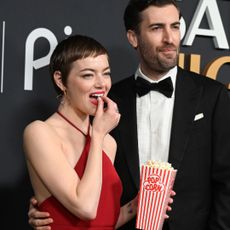 Emma Stone wears a bright red Louis Vuitton gown and fills her pockets with popcorn at SNL 50th Anniversary