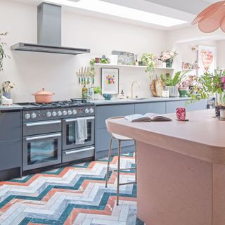 kitchen extension with colourful marble chevron flooring and pink concrete island and dark blue cabinetry