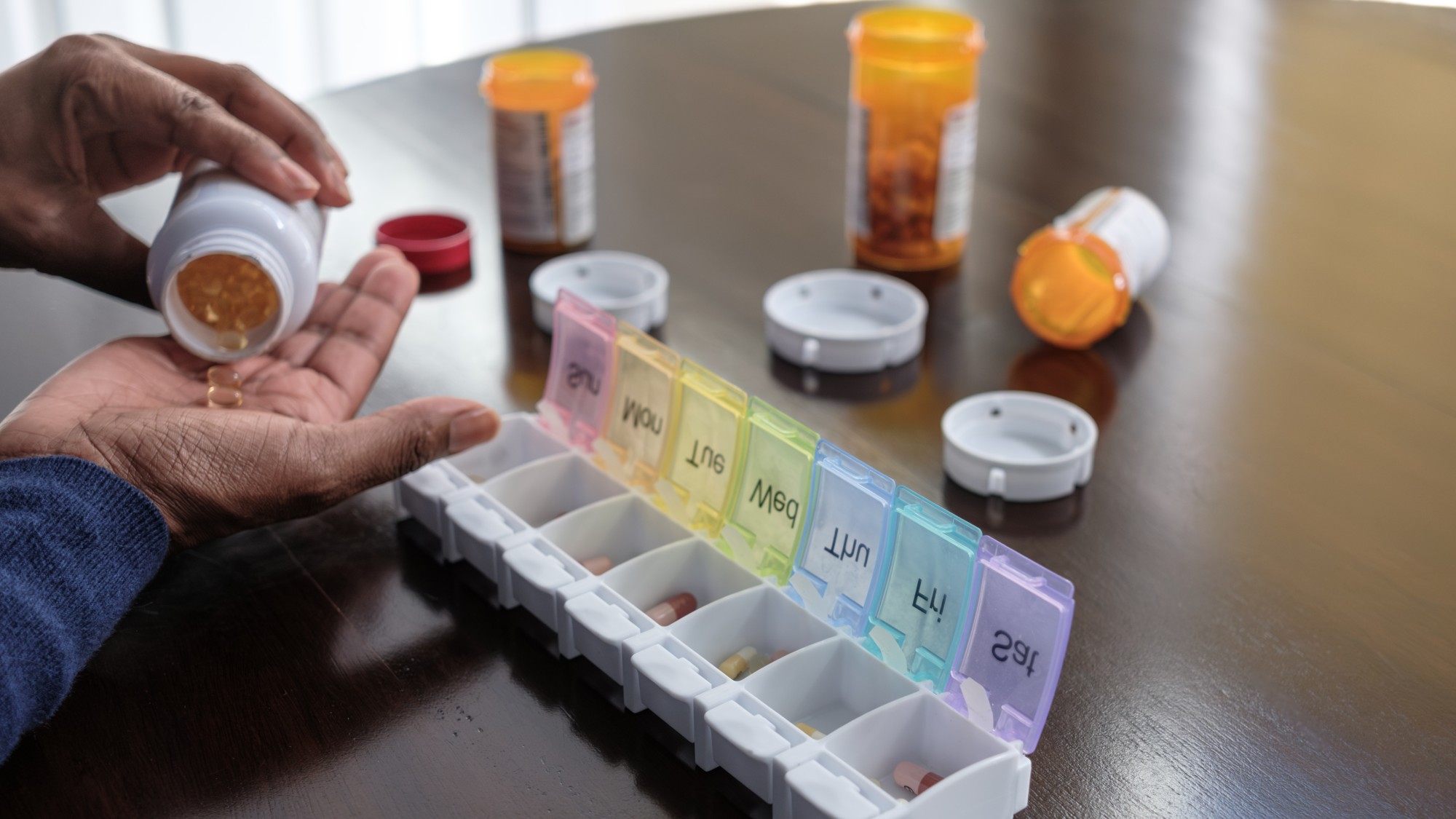 Close-up of black woman sorting her pills in organizer