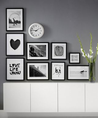 room with grey wall clock and picture frames and white cabinet