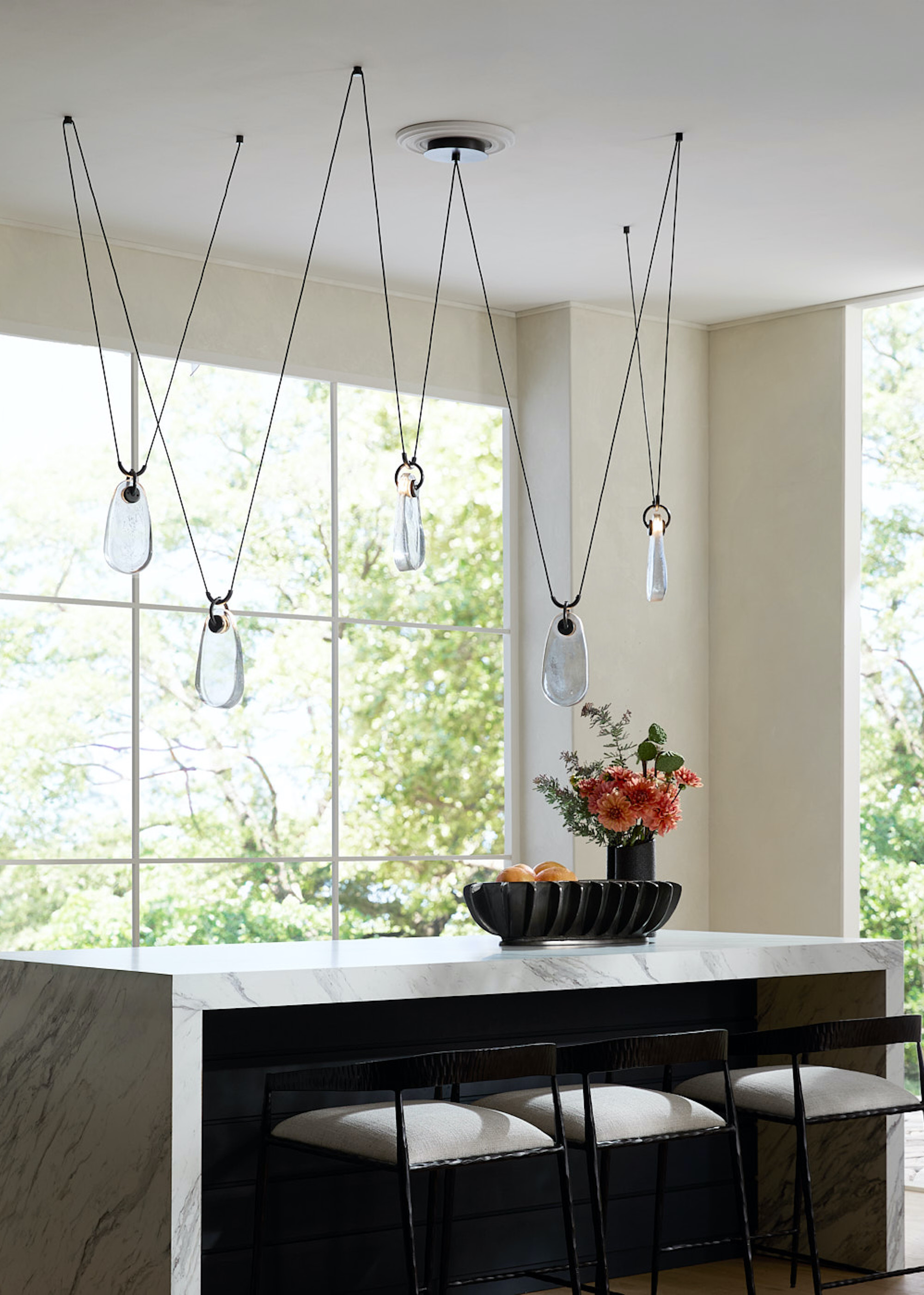 marble island with suspension pendants above the island hanging and beside the island are three bar stools