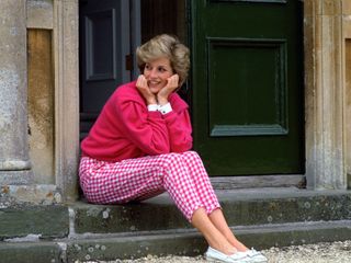 Princess Diana wearing a pink cardigan and gingham trousers on the steps of Highgrove House