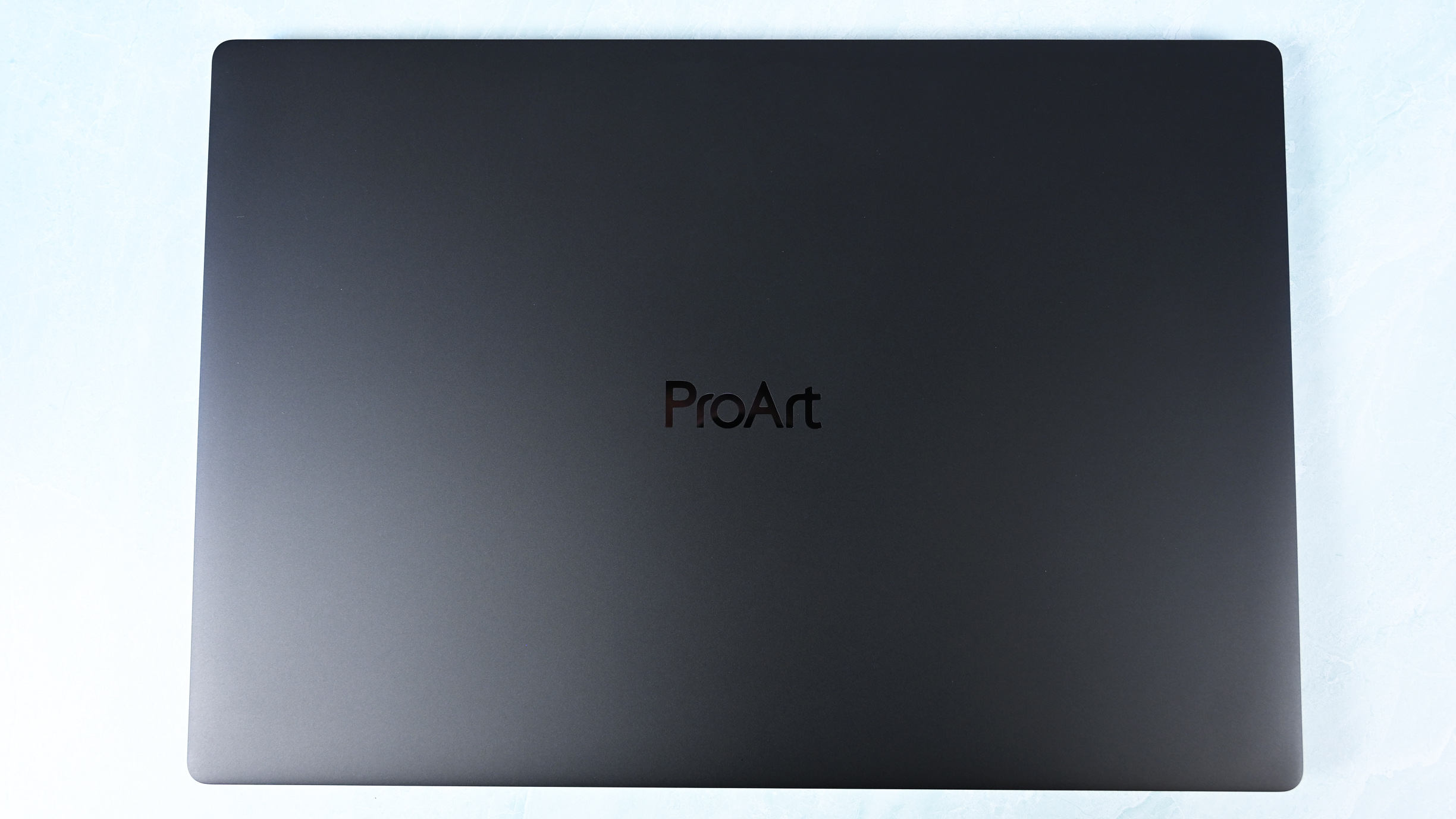 Top-down view of the closed ASUS ProArt P16 laptop featuring a minimalist matte black lid with a subtle centered ProArt logo.