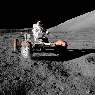 Astronaut sitting in the lunar roving vehicle on the surface of the moon.