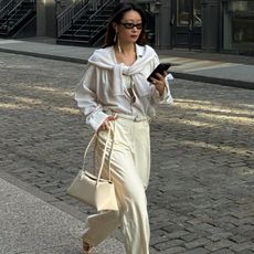 Woman walks down the street in NY in an all white outfit and Alaia Le Teckel Bag.