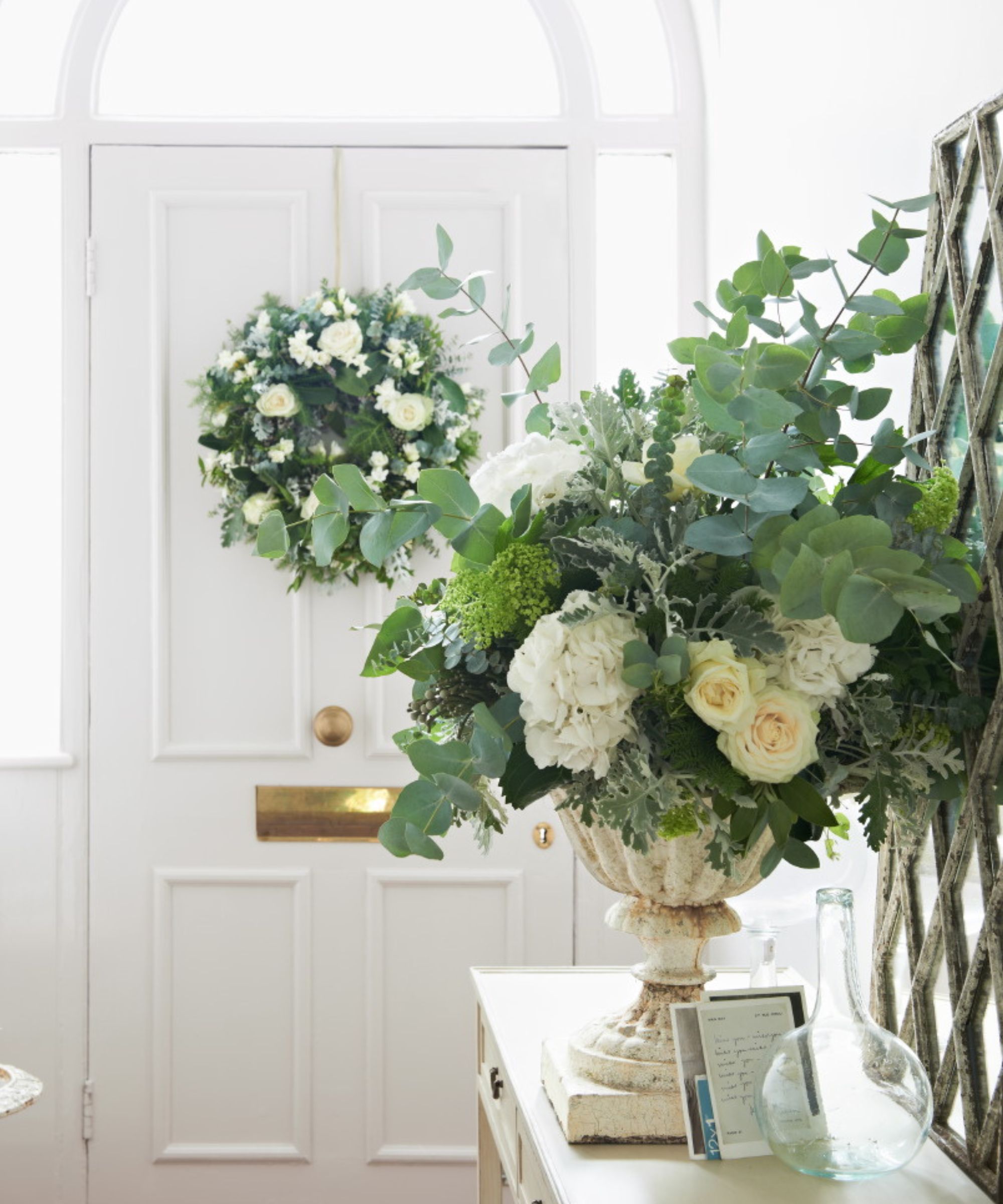 White roses and greenery in a vase in a hallway