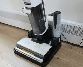 Close-up of Tineco Floor One S7 steam wet-dry vacuum plugged into mains outlet on hardwood flooring