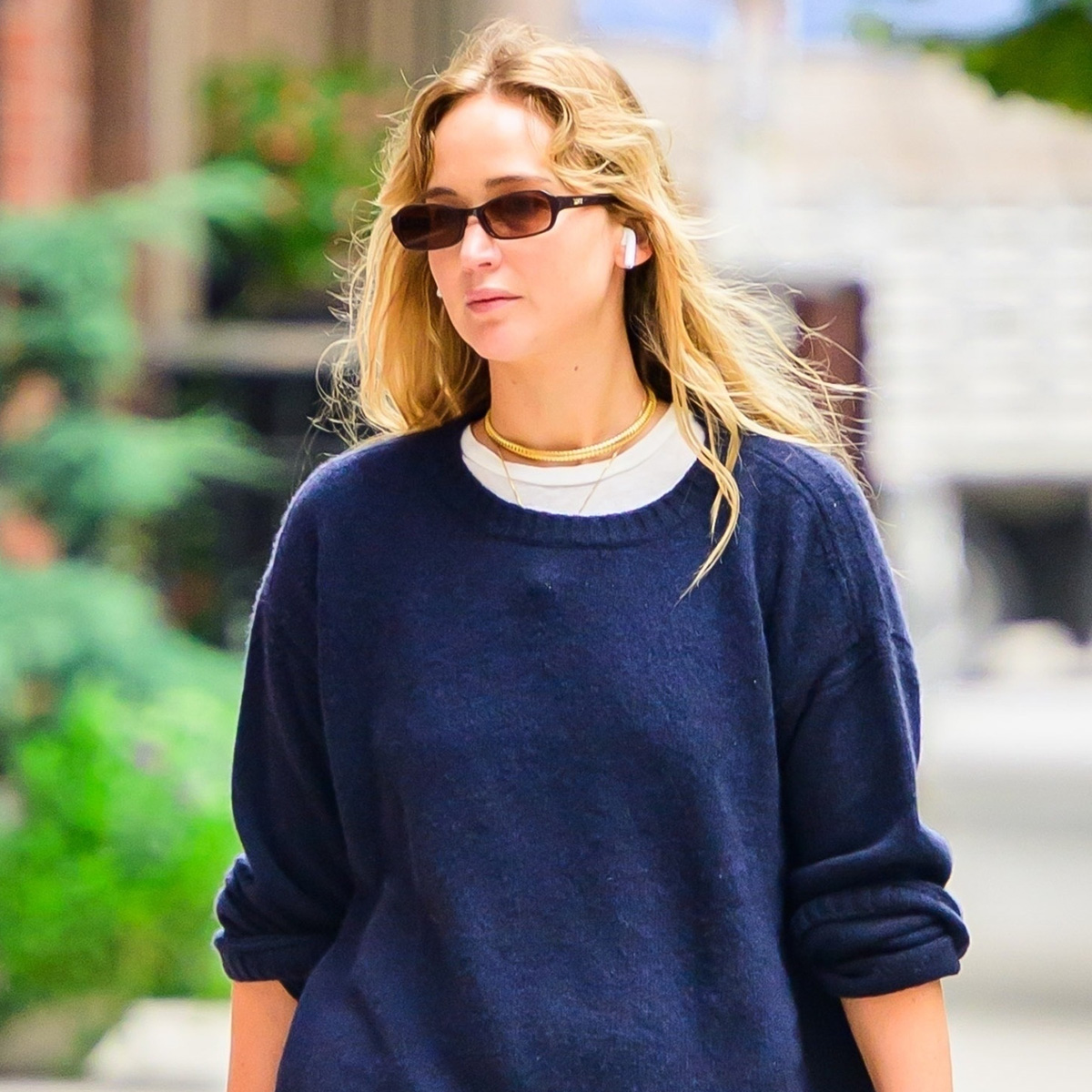 Jennifer Lawrence wearing a navy sweater, red track pants, studded bag, and flat mules in NYC