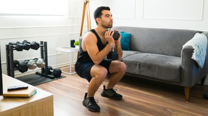 A man performing a goblet squat during a strength training workout at home 