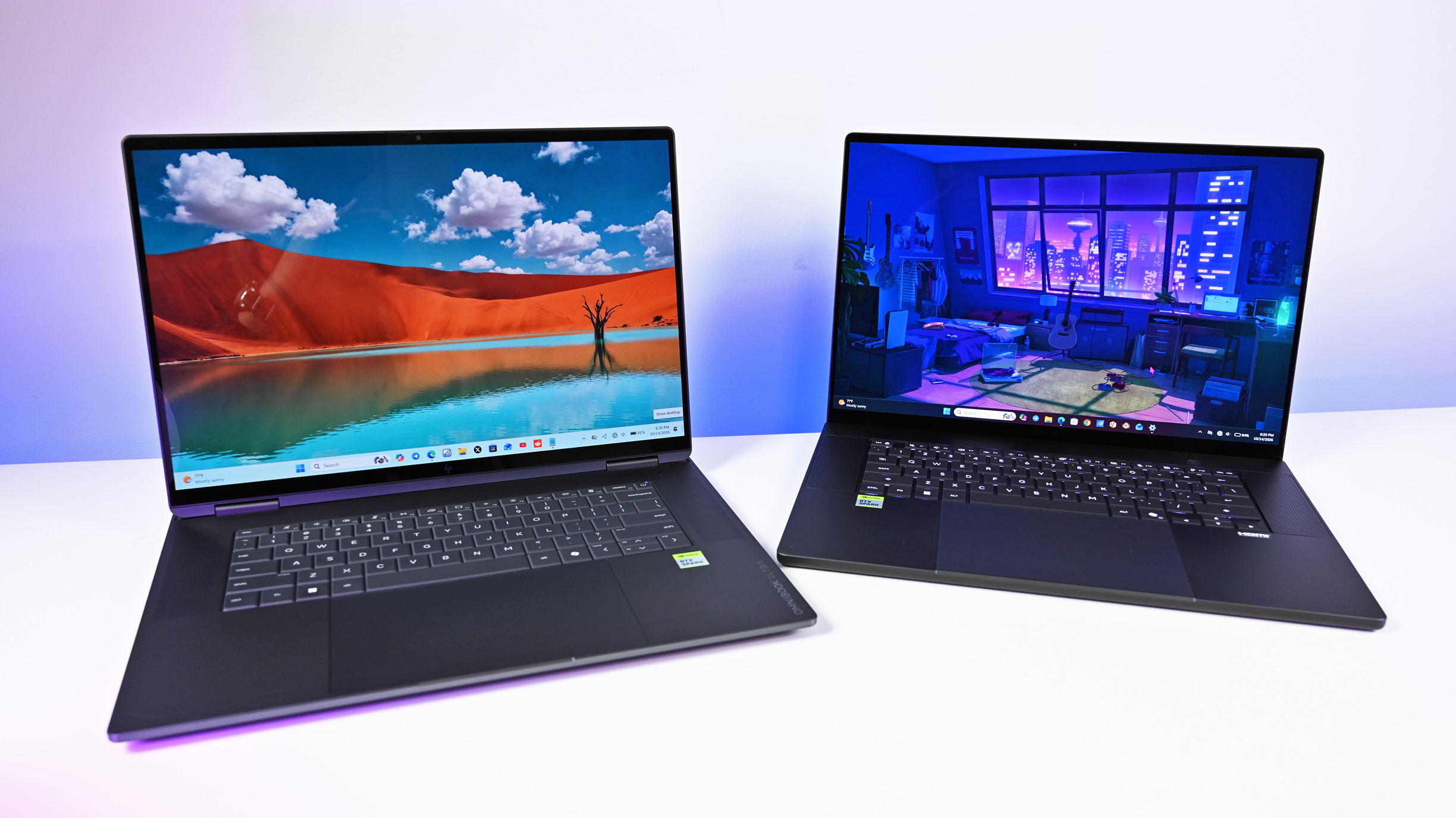 An HP OmniBook laptop on the left and the ASUS ProArt P16 on the right, open side by side on a desk displaying colorful desktop wallpapers.