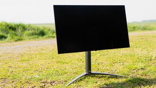 A black Acer Predator X27U monitor sitting on a sunny grass field