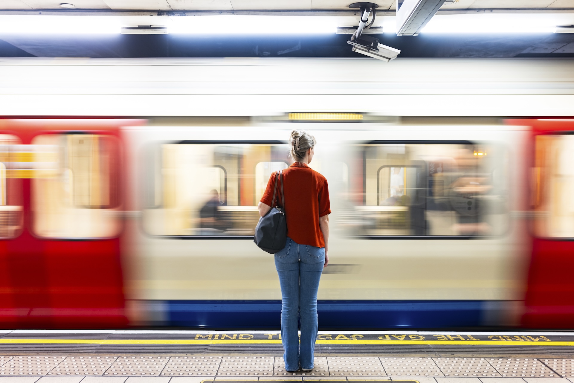 A woman standing near a moving train on the tube