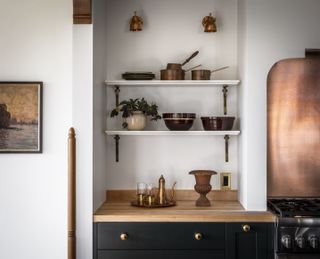 A white kitchen with butcher block countertop and brass