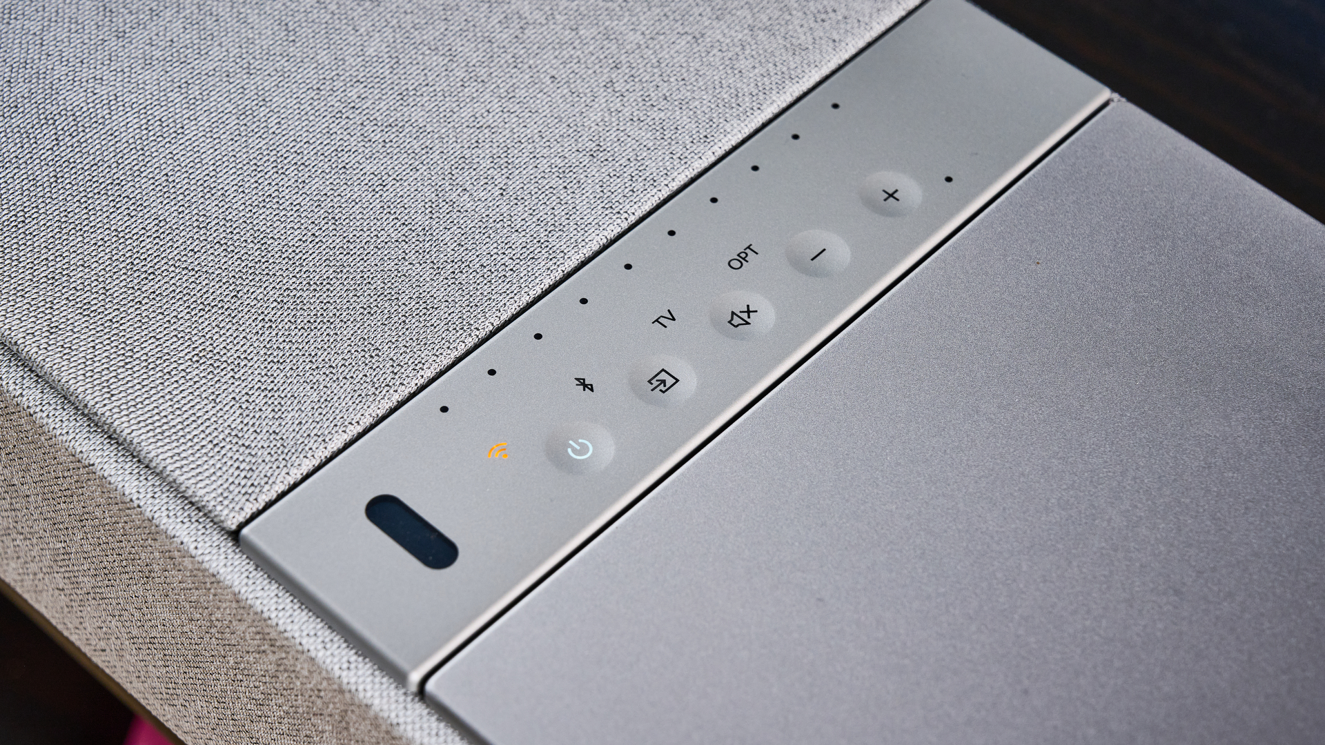 the KEF XIO soundbar in gray photographed with a TV and the Tom's Guide blue background