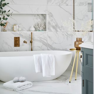 Modern bathroom with large format marble tiles on the walls and floors and a statement freestanding bath