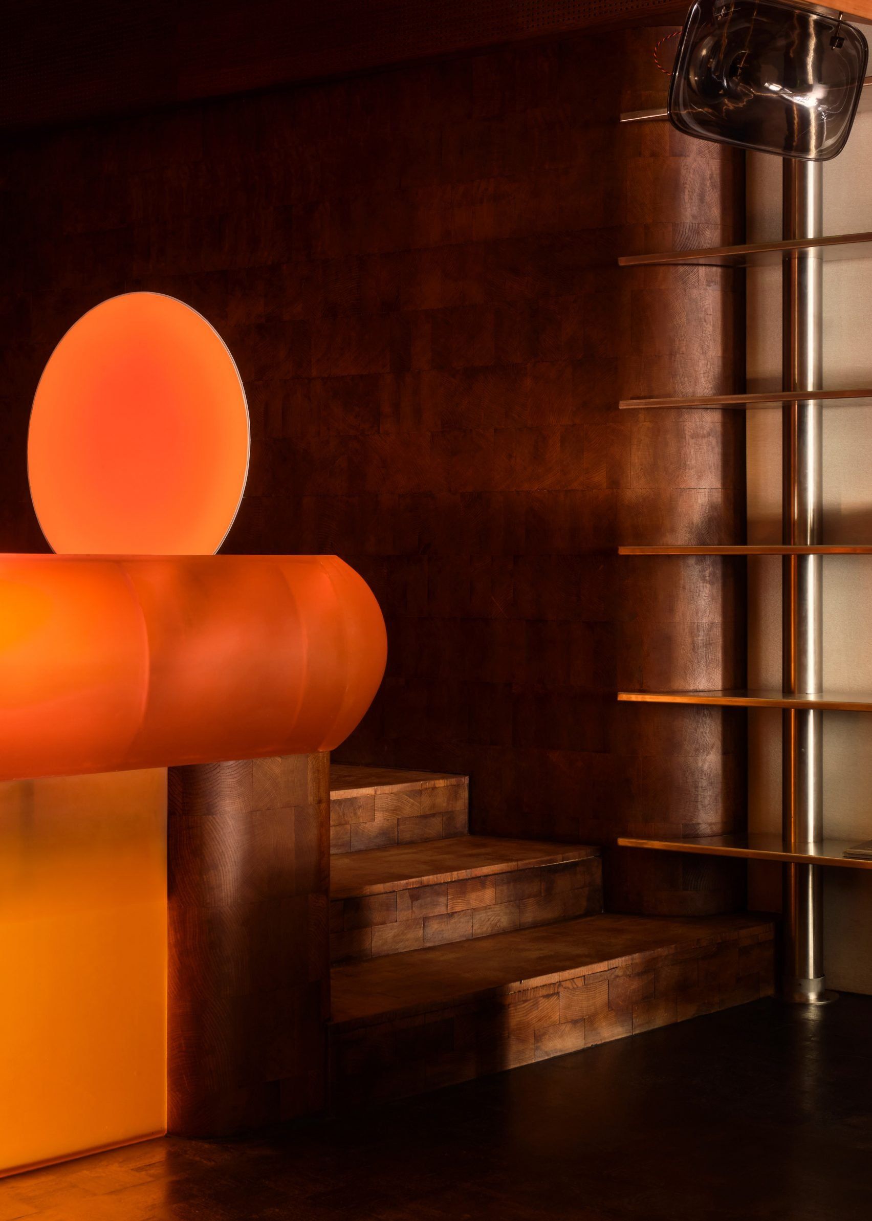 A vibey record bar with wood-clad walls, chrome accents, and a glowing, orange futuristic counter.