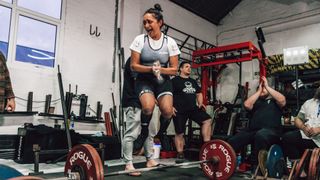Poorna Bell, having just completed a 130kg deadlift, jumping in excitement surrounded by other members of her weightlifting team