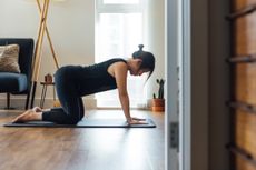 Woman on her hands and knees on an exercise mat in a home