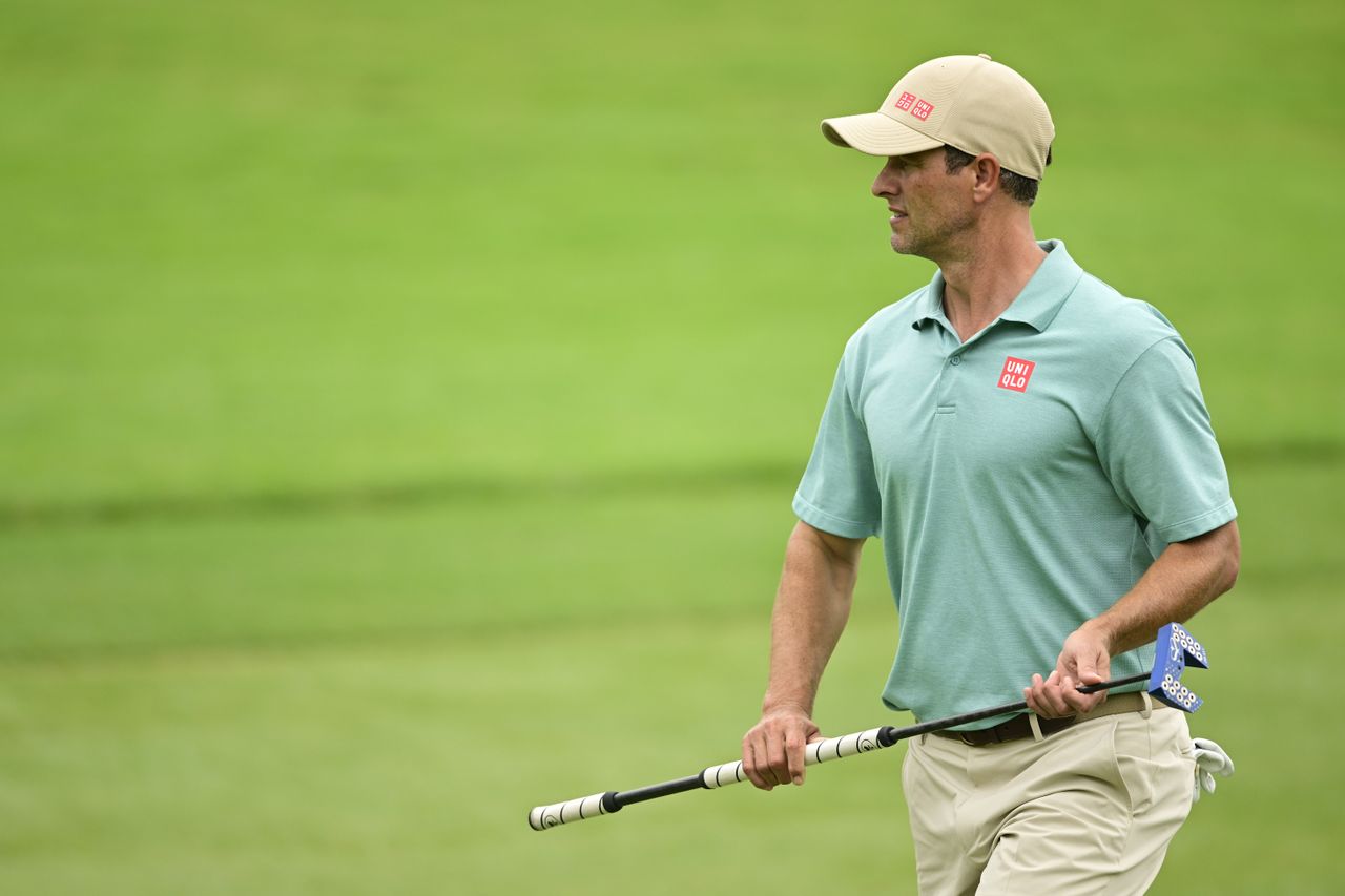 Adam Scott looks on whilst holding a putter