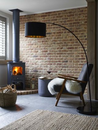 living area with an exposed brick wall, cosy stove and fluffy rug