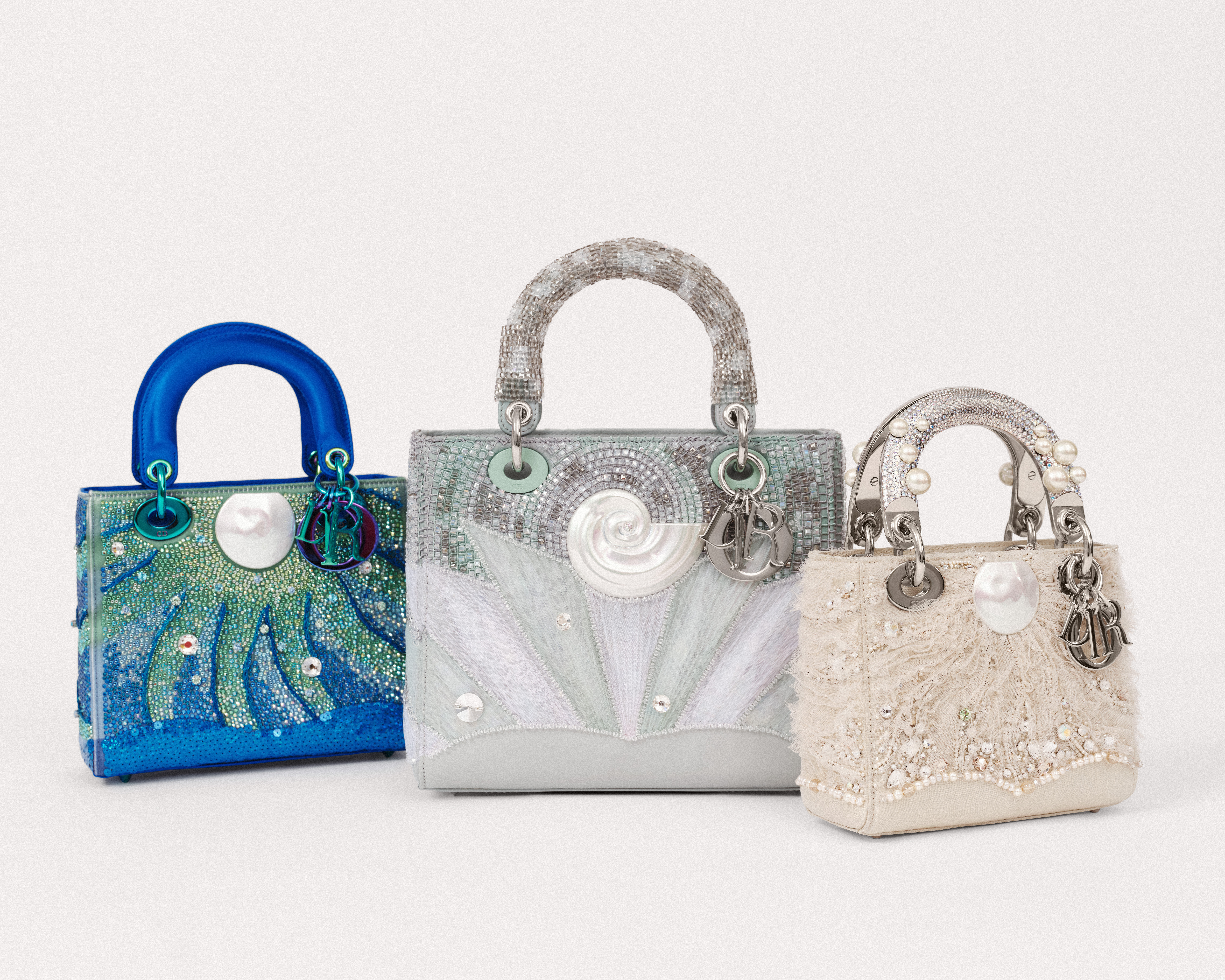 three embellished lady dior art bags on a table