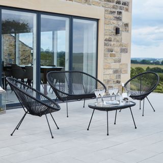 Black metal table on patio with round chairs