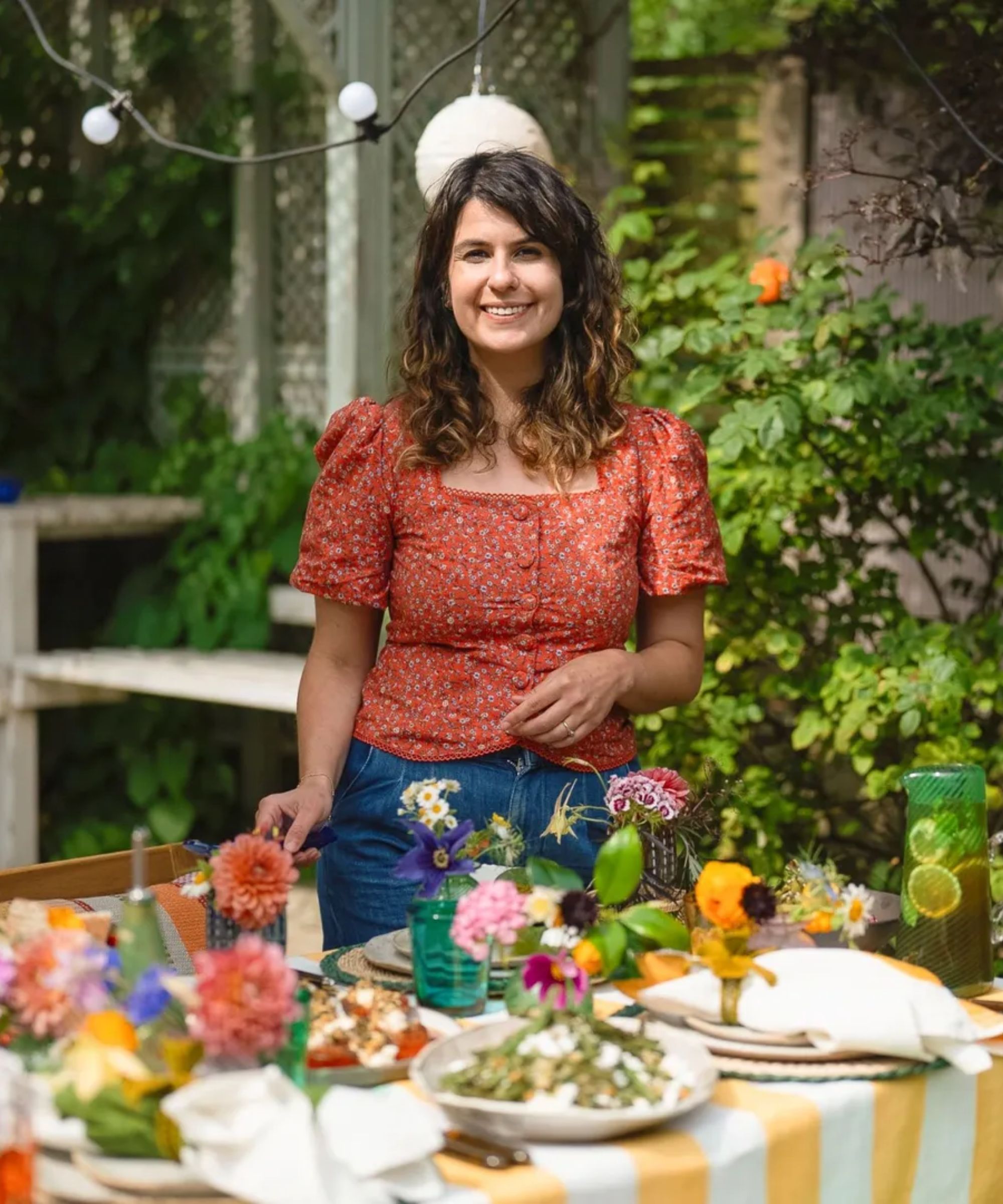 Noor Murad serving food at her summer outdoor table styled with flowers and colorful accessories