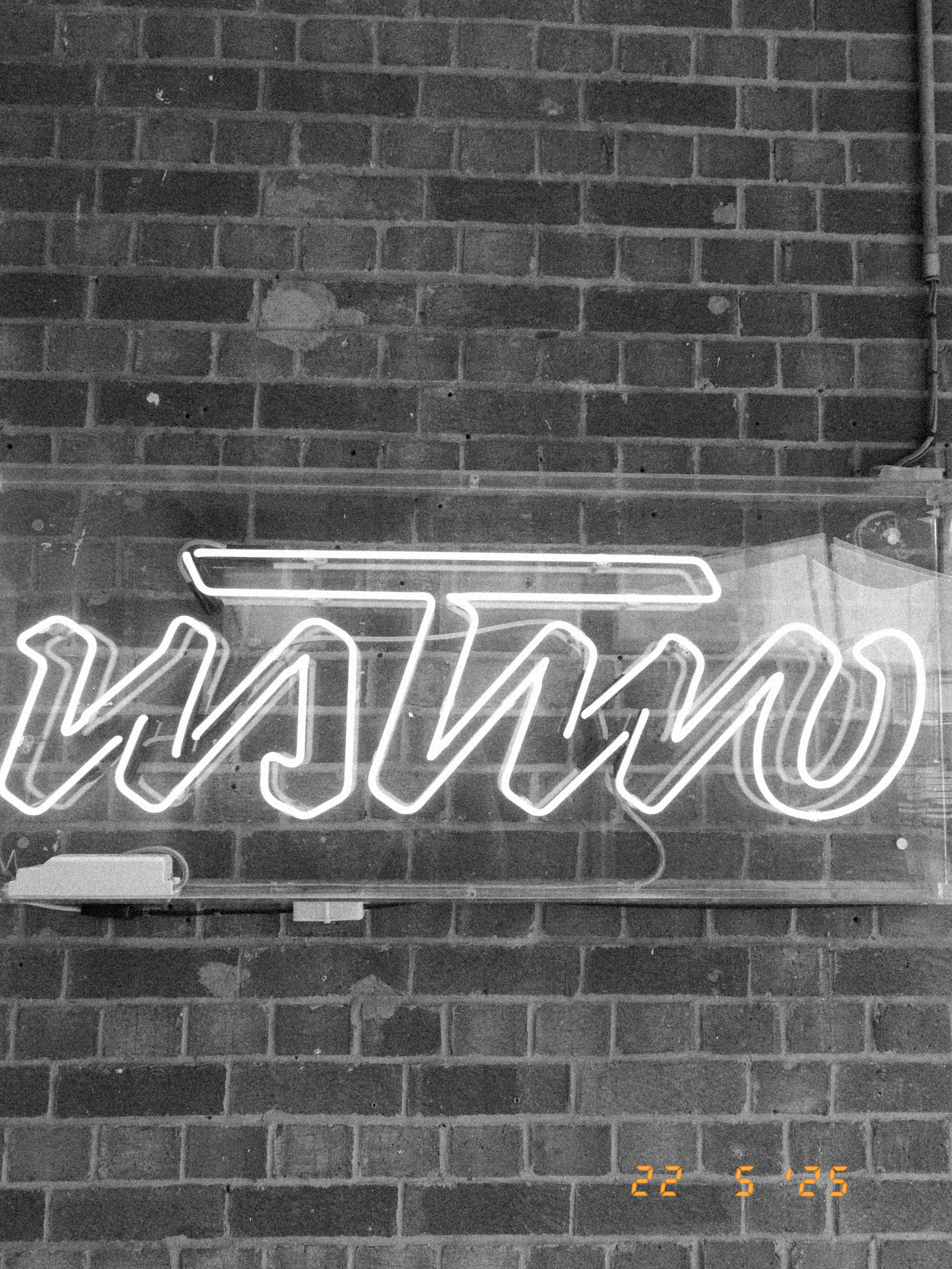 A neon sign in front of the brick wall