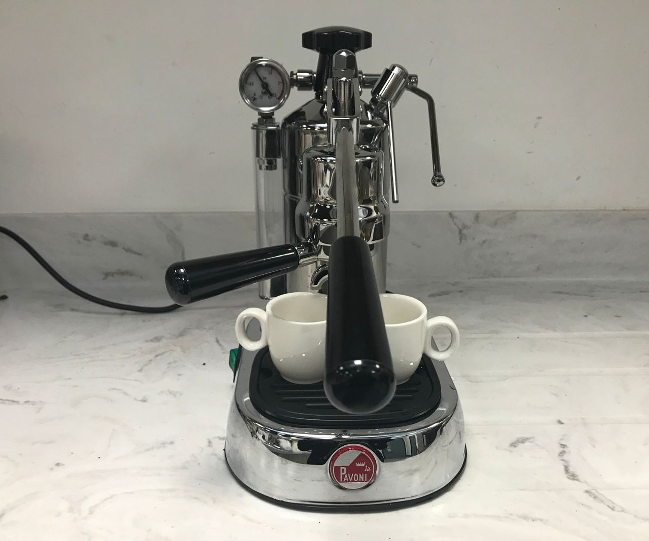 A professional grade stainless steel espresso machine on a white kitchen counter.