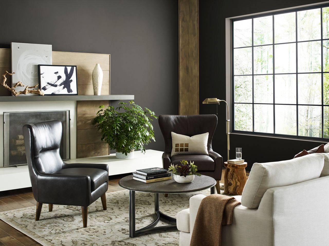 A living space with a large window, dark walls, and leather chairs