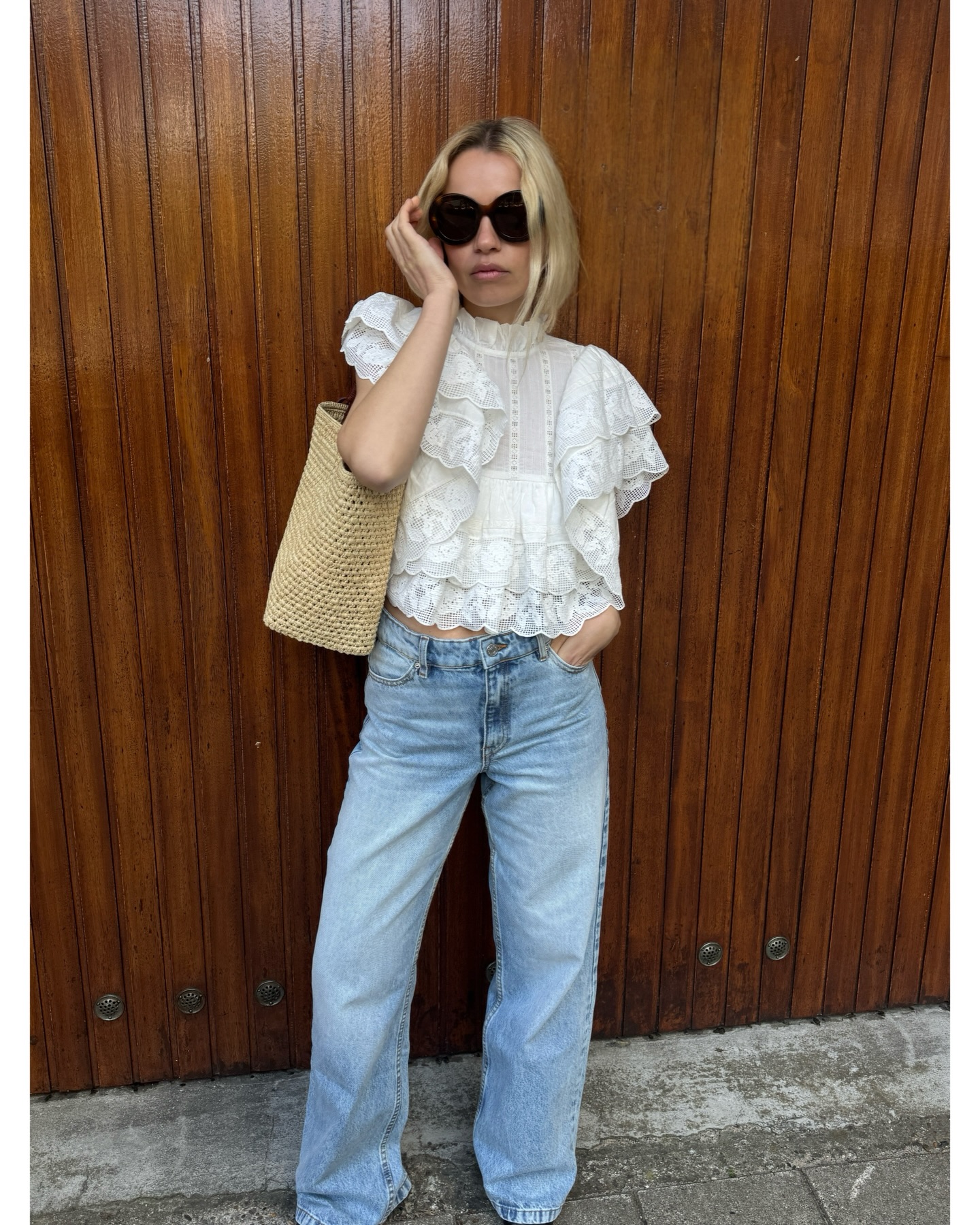 An image of @stephaniebroek wearing a peasant top, one of the biggest blouse trends of 2026, with a pair of blue jeans and woven bag.