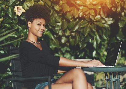 Lady Sitting In A Garden Typing On A Laptop