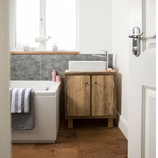 White bathroom with old wooden vanity cabinet and grey tiles