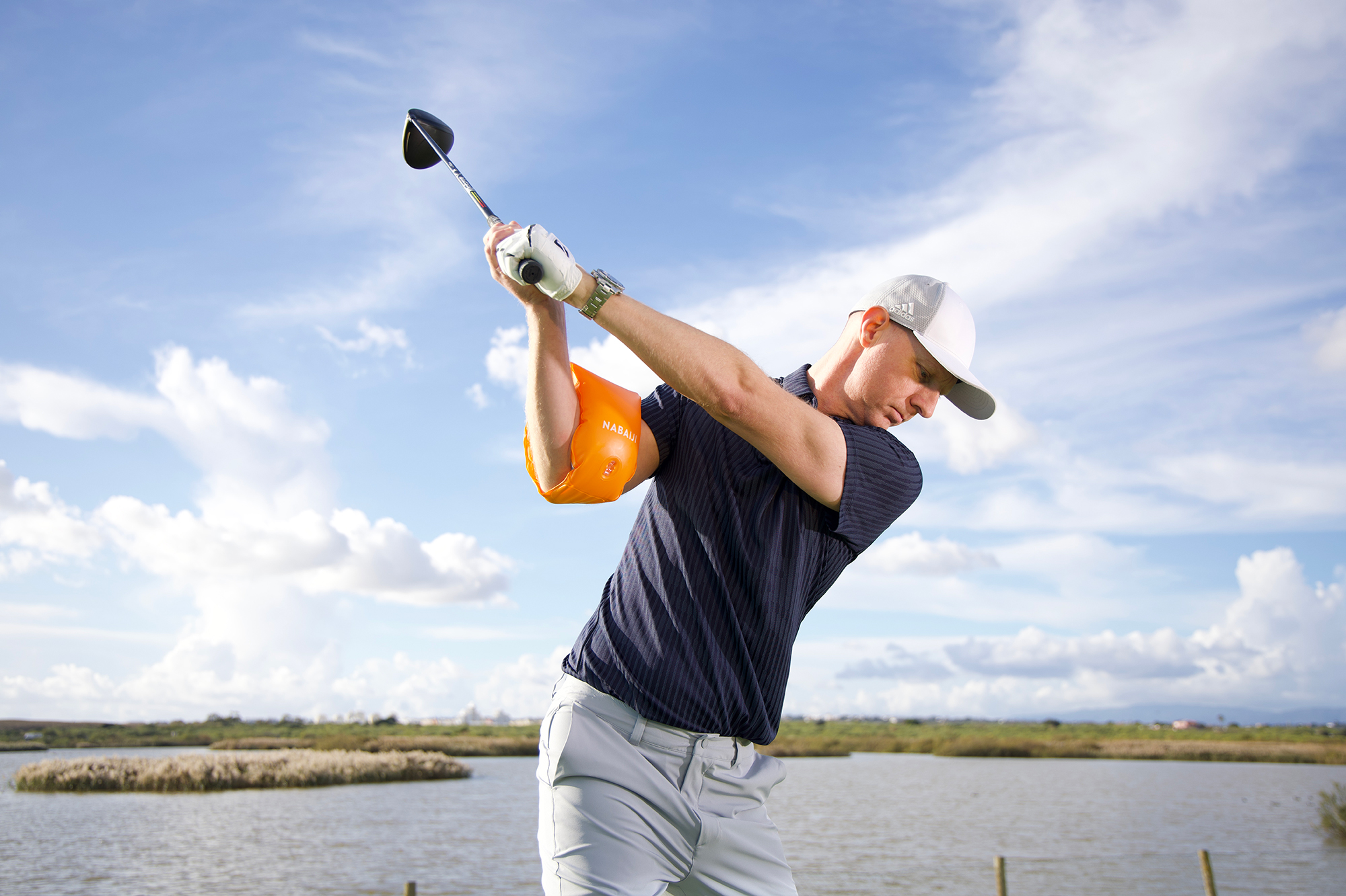 Ged Walters demonstrating a drill to improve trail arm position by using an inflatable water wing or armband to show how the trail arm should fold in the backswing