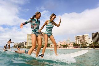 Courtney Conlogue teaching blogger, Kaitlynn Carter, how to surf in Waikiki.